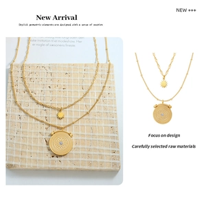 Detail of layered gold titanium steel necklace featuring sunburst coin and star pendant