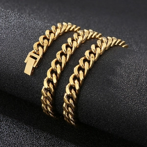 Detail of golden cuban link chain with square clasp on a textured dark pedestal