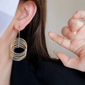 Close-up of model wearing gold multilayer spiral hoop earrings with metallic finish