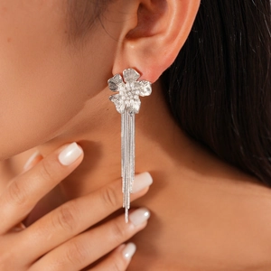 Close-up of floral tassel earrings with silver finish worn by a model in a high-detail shot