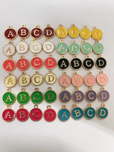 Detail of colorful round enamel letter charms A, B, C, D in various vibrant alloy finishes