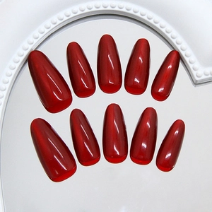 Deep red cat eye press-on nails in long almond shape on a vintage mirror tray