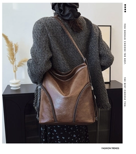 Detail of soft brown leather bag showing decorative side zipper and premium PU texture