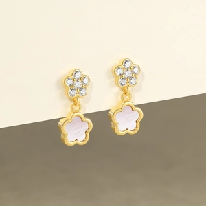 Detail of gold flower earrings with white shell petals and sparkling cubic zirconia stones