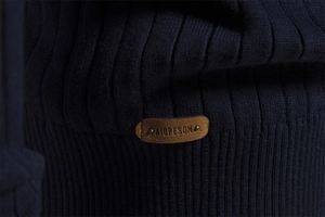 Detail of dark blue knit sweater showing vertical ribbed texture and leather logo patch