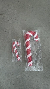 Detail of red and white Christmas foam candy cane ornaments with glitter on grey background