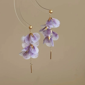 Detail of purple fabric petal earrings with gold tassels and elegant floral design