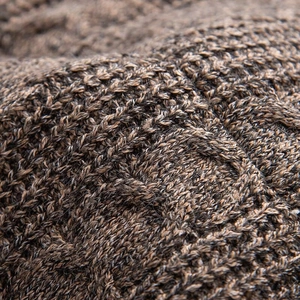 Detailed close-up showing thick cable knit texture and warm brown melange yarn fabric
