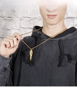 Close-up of a gold bullet pendant necklace on a male model with a sleek snake chain