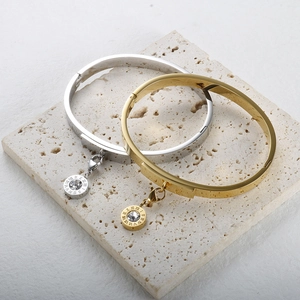 Detail of gold and silver bangles with Roman numeral charms and inset rhinestones