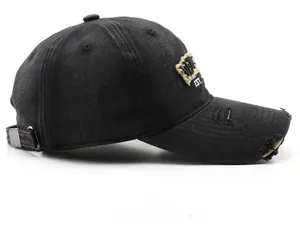 Detail of distressed black washed cotton baseball cap with vintage embroidery and metal buckle