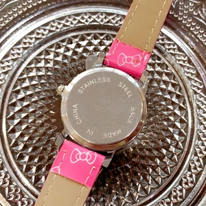 Macro view of stainless steel watch back case and pink leather strap with kitty patterns