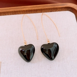 Vue détaillée des boucles d'oreilles cœur noir avec de longs crochets dorés incurvés