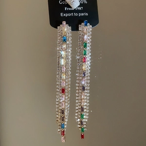 Macro shot of elegant long tassel earrings with multicolored zircon stones in luxury style