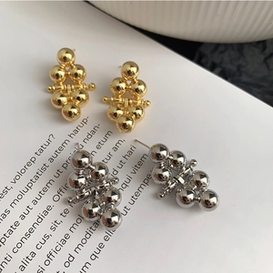 Detailed view of stacked gold and silver metallic ball earrings on artistic paper
