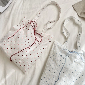 Detail of red and blue heart patterns on striped canvas tote bags with drawstring closings