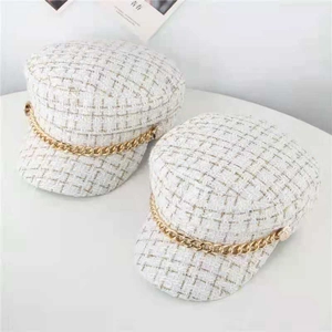 Detail of tweed newsboy cap with gold chain ornament and vintage metal buttons