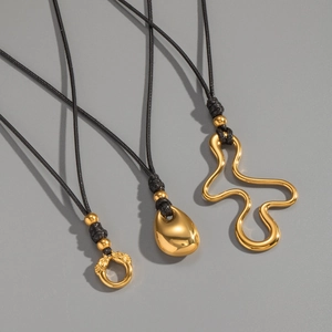 Détails de trois pendentifs dorés minimalistes aux formes de gouttes et courbes variées