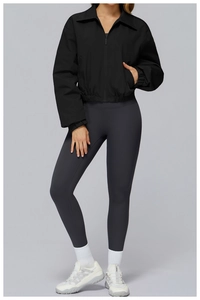 Detail of a black cropped bomber jacket with high-waisted leggings and platform sneakers