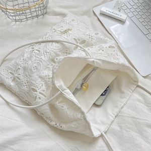 Detail of white floral lace tote bag featuring a secure zipper inner pocket for phone