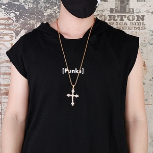 Pendentif croix dorée hip hop avec strass blancs porté par un mannequin de rue