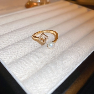 Detail of gold dragon ring featuring sparkling clover stones and a round pearl accent