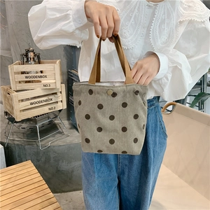 Detail of light brown corduroy tote bag with dark polka dots and metal snap closure
