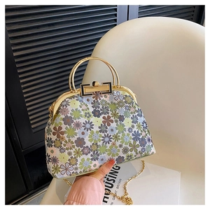 Detailed close-up of retro floral shell bag with gold metal clasp and chain strap
