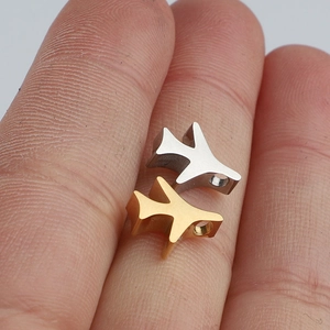 Macro-opname van gouden en zilveren vliegtuigbedeltjes met 1,8 mm gat tussen de vingers