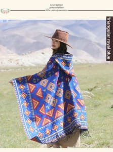 Détail d'un poncho à capuche bleu roi bohème avec motifs géométriques et franges