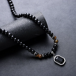 Tiger eye beaded necklace for men with black octagonal gemstone pendant on textured background
