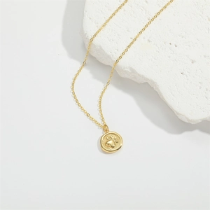 Minimalist gold necklace with a round paw print pendant on a white stone background