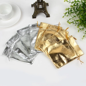 Gold and silver drawstring jewelry gift pouches displayed with decorative items