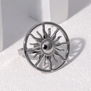 Close-up of hollow sunburst stainless steel ring in polished silver on stone texture