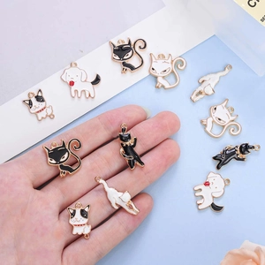 Hand holding cute cartoon cat and dog enamel charms with gold edges on blue background