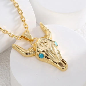 Gold bull skull necklace with turquoise eyes and floral carving on white stone