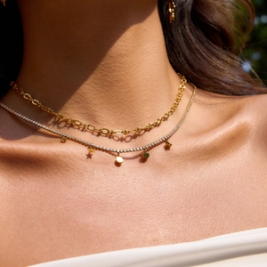 Detail view of double-layer gold necklace with star and heart charms on model