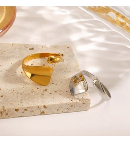 Close-up of golden and silver irregular abstract streamline rings on beige travertine stone
