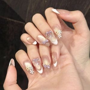 Long almond press-on nails with purple bows, pearls, and golden cat eye finish