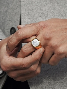 Close-up of men's gold signet ring with white marble stone inlay on hand