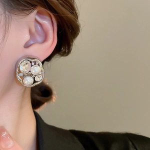 Close-up of wavy silver stud earring with pearls and sparkling cubic zirconia on model