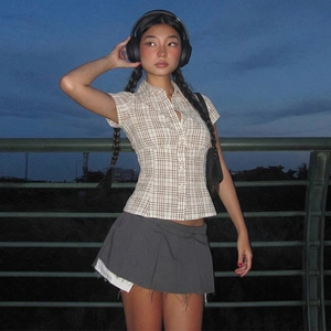 Outdoor night shot of brown checkered short-sleeve shirt and dark grey pleated skirt