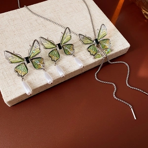 Detail of green gradient butterfly necklace with shimmering wings and teardrop pearl