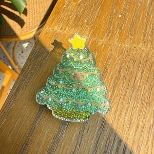 Detailed macro view of a Christmas tree-shaped resin clip with green sequins and a star