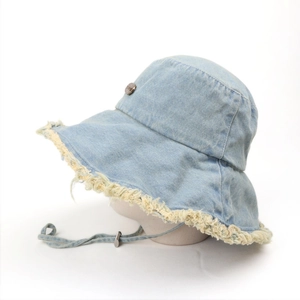 Detail of light blue denim bucket hat with frayed edges and adjustable chin strap