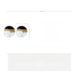 Détail de boucles d'oreilles rondes en résine avec texture marbre noir et blanc et dorures