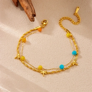Macro detail of gold double-layered bracelet featuring dragonfly charms and colored beads