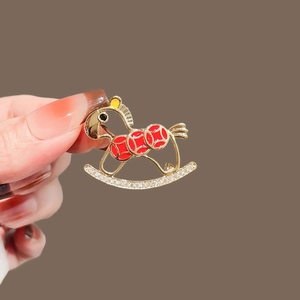 Elegant gold rocking horse brooch with red enamel rings and sparkling white rhinestones