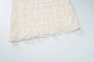 Détail de l'ourlet à volants superposés et de la texture du tissu sur cette robe longue crème