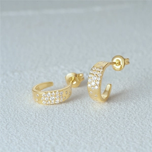 Macro view of C-shaped gold-plated silver earrings with sparkling zircon stones and S925 stamp